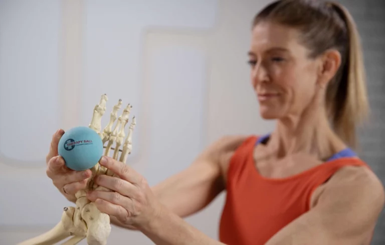 Adjusting the therapy ball, the woman checks its correct placement for the exercise.