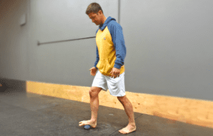 Man using a therapy ball for self-massage on his foot.