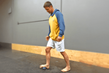 Man using a therapy ball for self-massage on his foot.