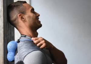 Man holding a sports ball on his upper back and shoulder.