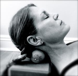 A woman reclines on her back, resting her head comfortably on a ball.