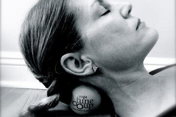 A woman reclines on her back, resting her head comfortably on a ball.