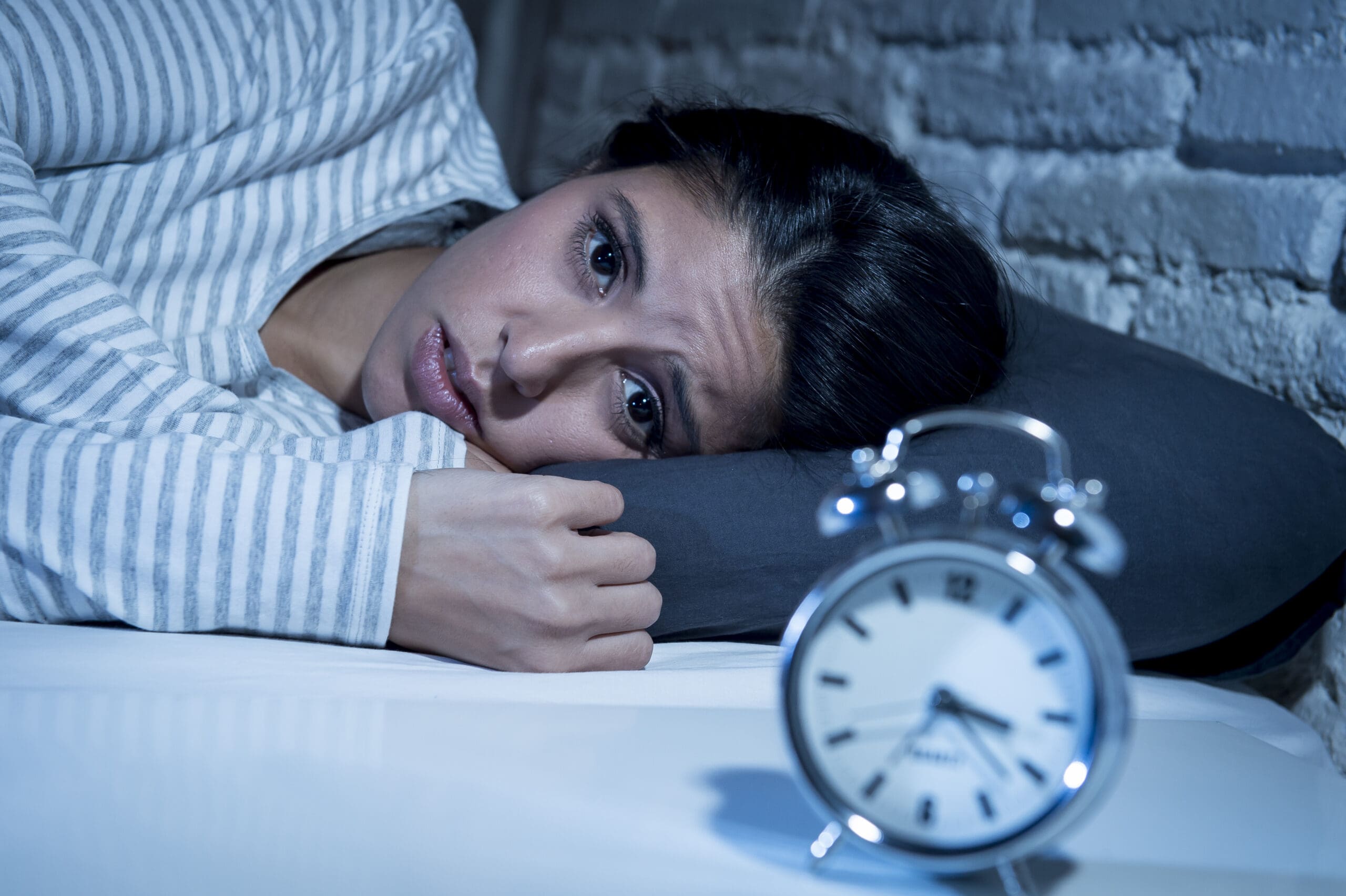 The woman looks restless, unable to sleep, her face showing discomfort.