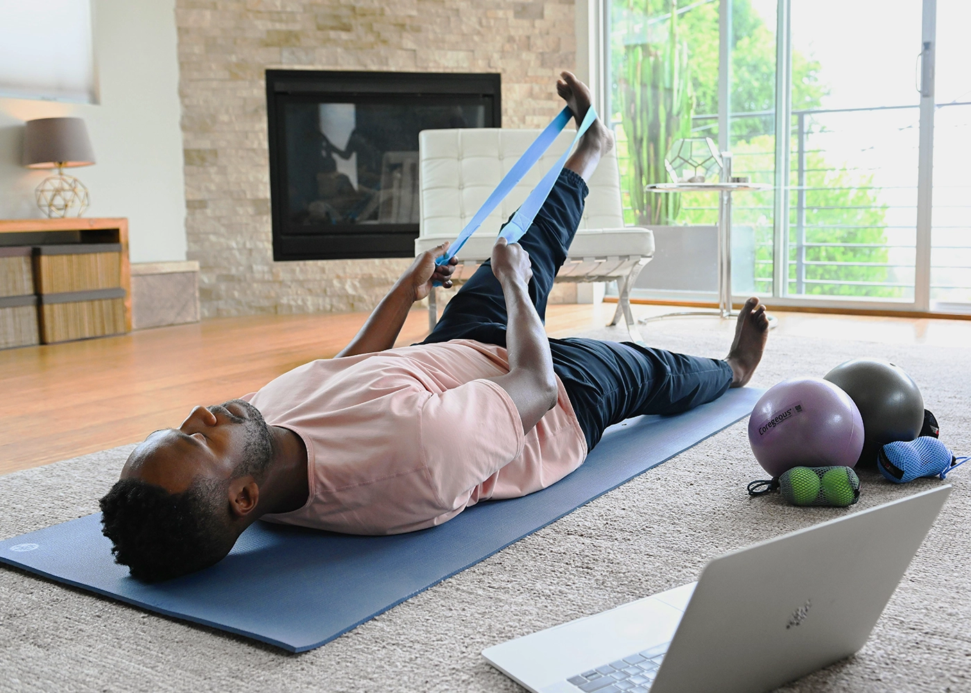A man comfortably lying on a yoga mat while engaging with his laptop,