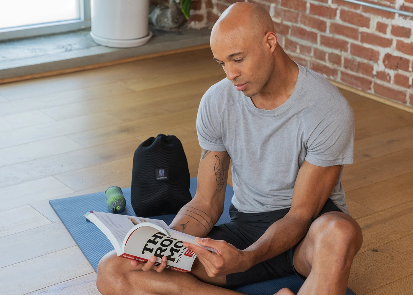 Man in studio reading The Roll Model with Massage Ball Kit in background