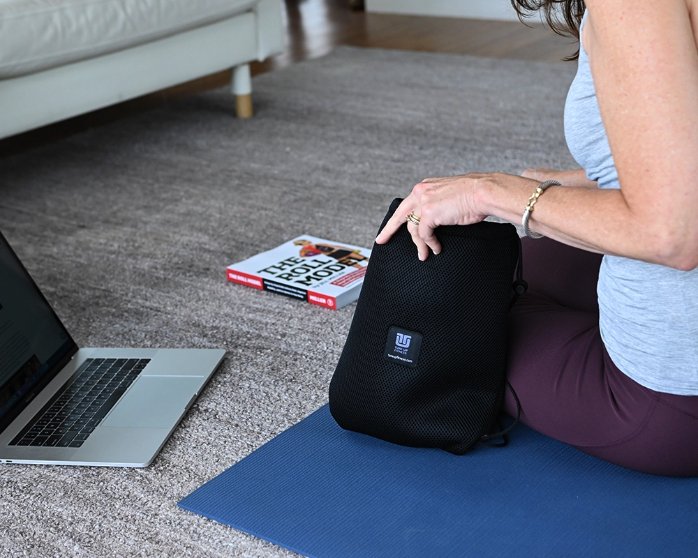 Woman reaching into Massage Ball kit bag with Roll Model Book in background