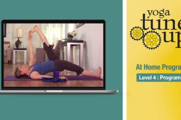 A woman uses a yoga block under her spine, lifting one leg while the other foot touches the wall, with "Yoga Tune Up Home Program" on the side.