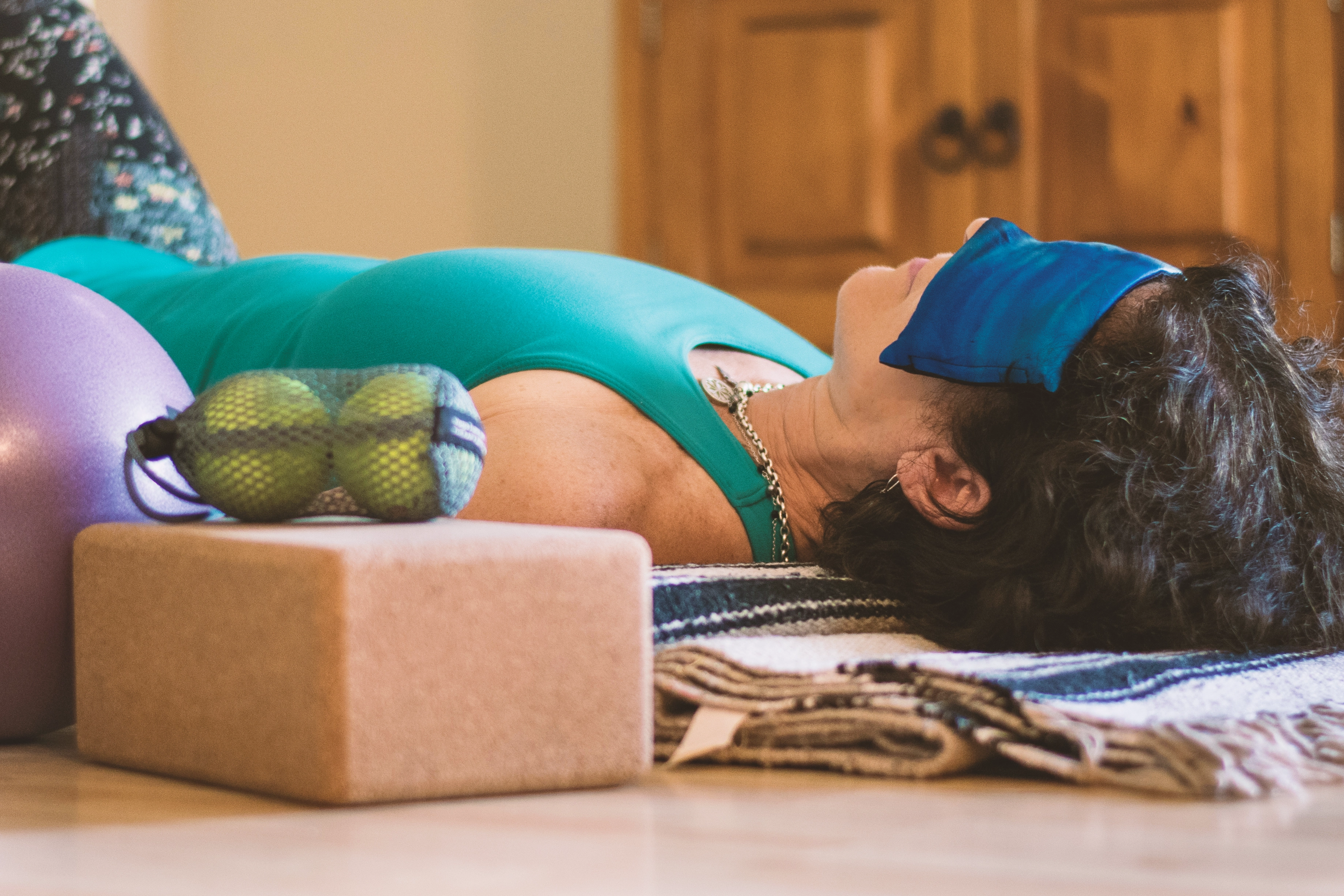 Photo: Woman in NSDR position, lying on back with sandbag over eyes in demi-corpse position, or legs bent and feet on the ground 