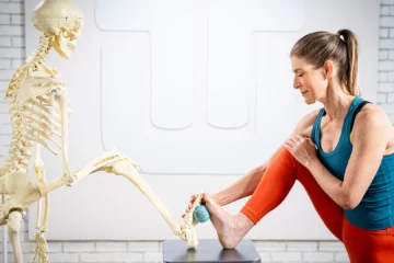 A woman stretches her foot alongside a skeleton, illustrating anatomy and flexibility in a unique and educational manner.