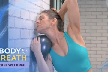 A woman in a teal sports bra, performing a stretching or yoga exercise.