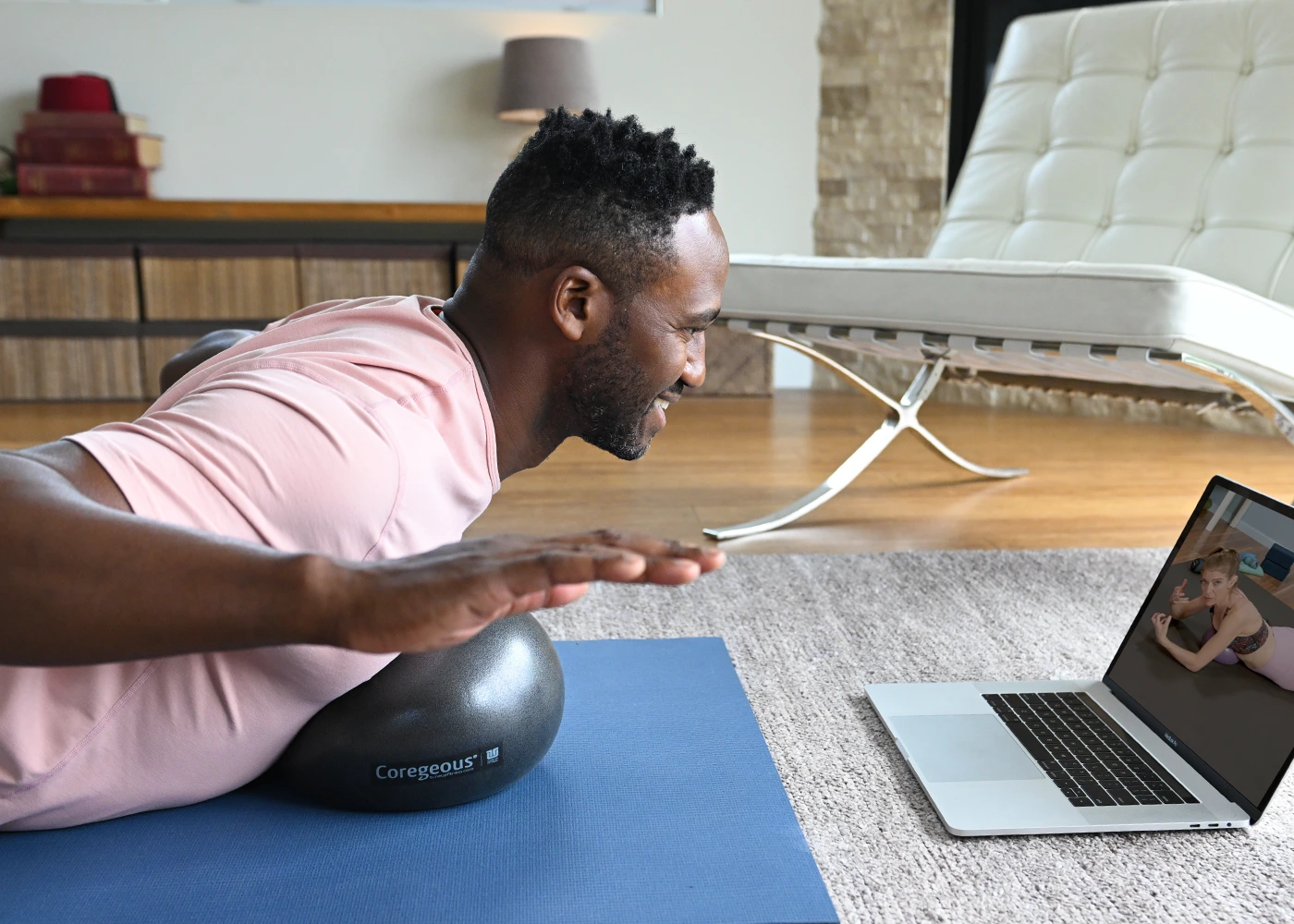 Pro_Club_Lifestyle_Image3 A man is lying on a blue yoga mat, performing a core exercise.