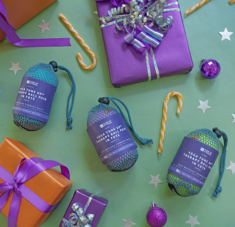 Featured Product Section Image #3 copy Tune Up Fitness therapy ball sets arranged with wrapped gifts and holiday decorations, highlighting festive self-care and wellness gifting.