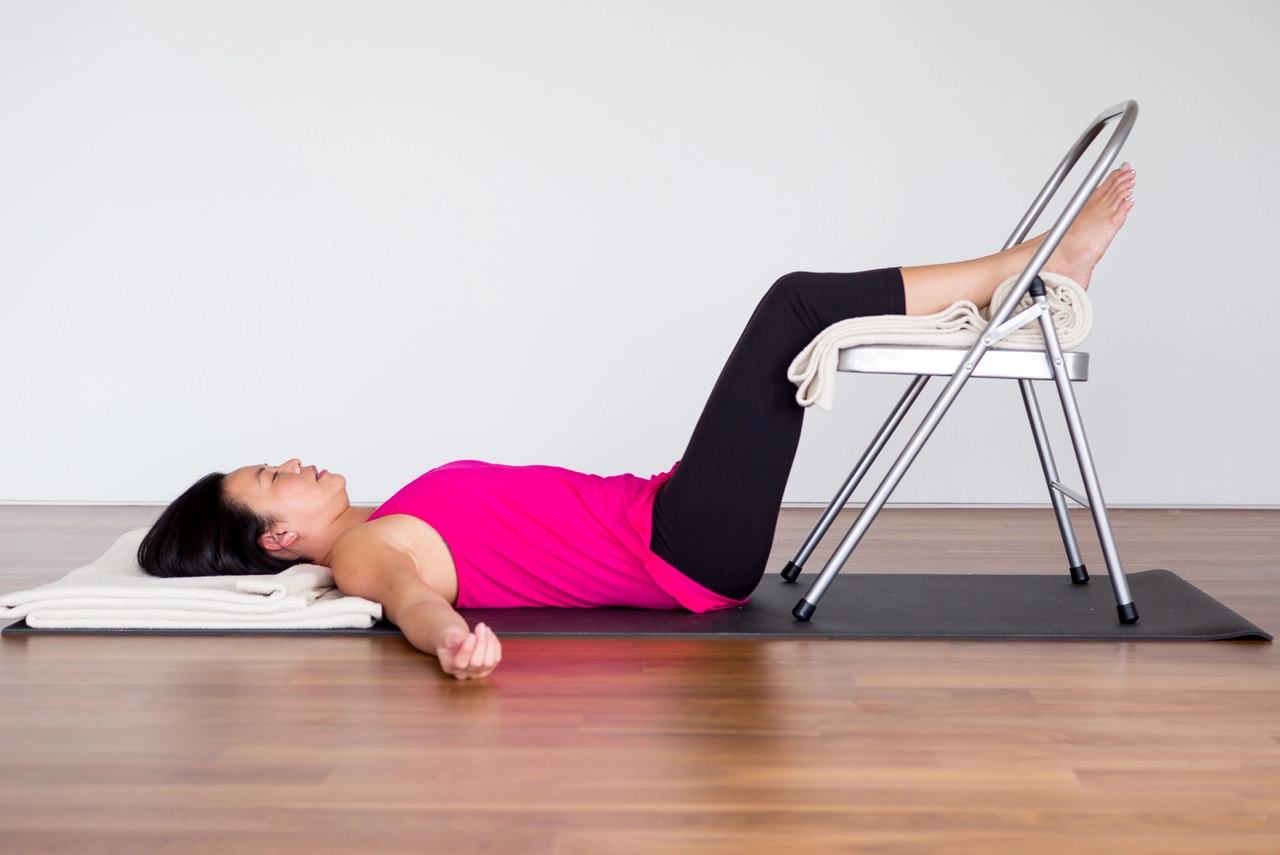 Woman in ardha savasana to provide self-care for her pelvic floor health.